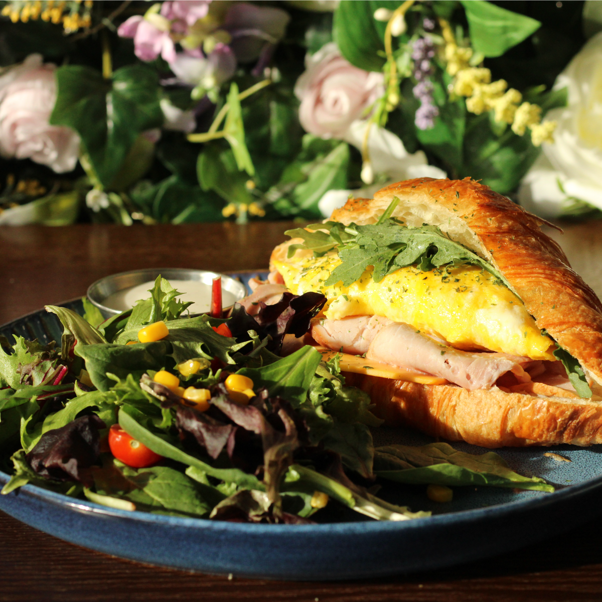 Breakfast croissant with eggs, ham and arugula, served with salad